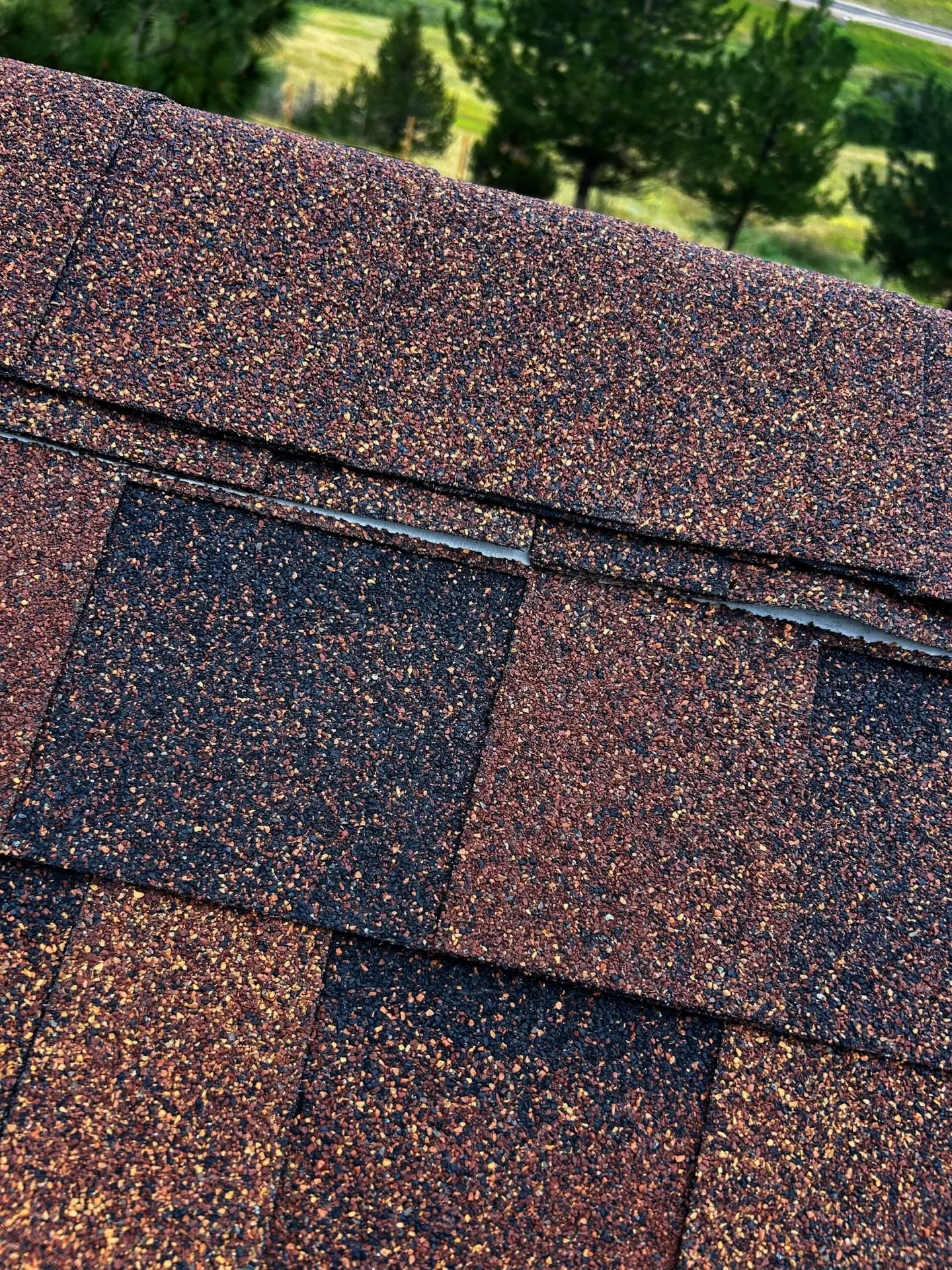 Close-up of asphalt roof shingles showing slight granule loss along the ridge cap, illustrating common granule shedding after installation