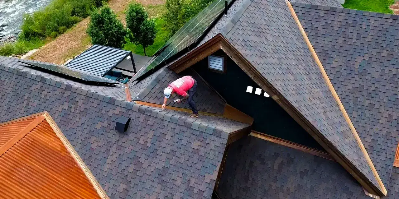 Professional roofer inspects an asphalt shingle roof in Colorado,