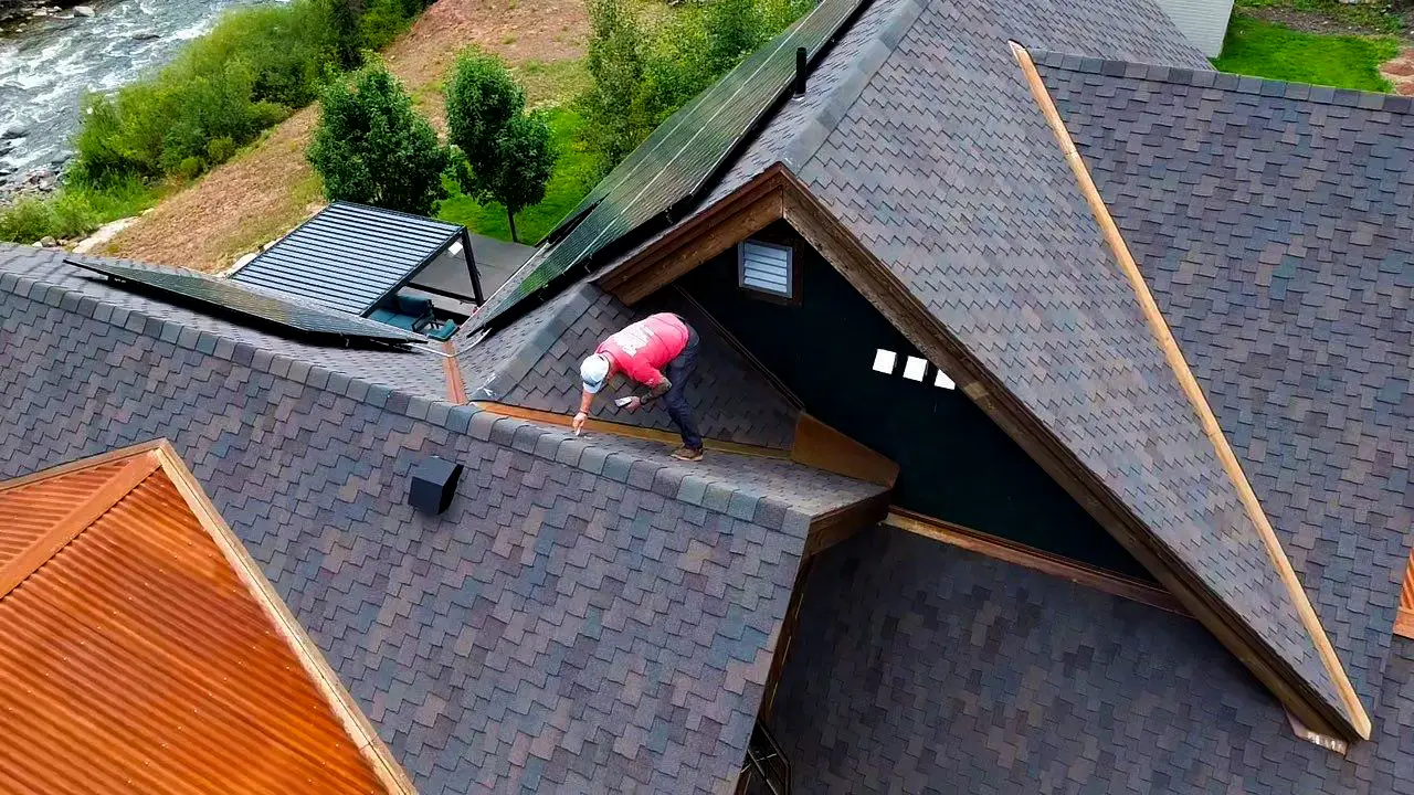 Professional roofer inspects an asphalt shingle roof in Colorado,