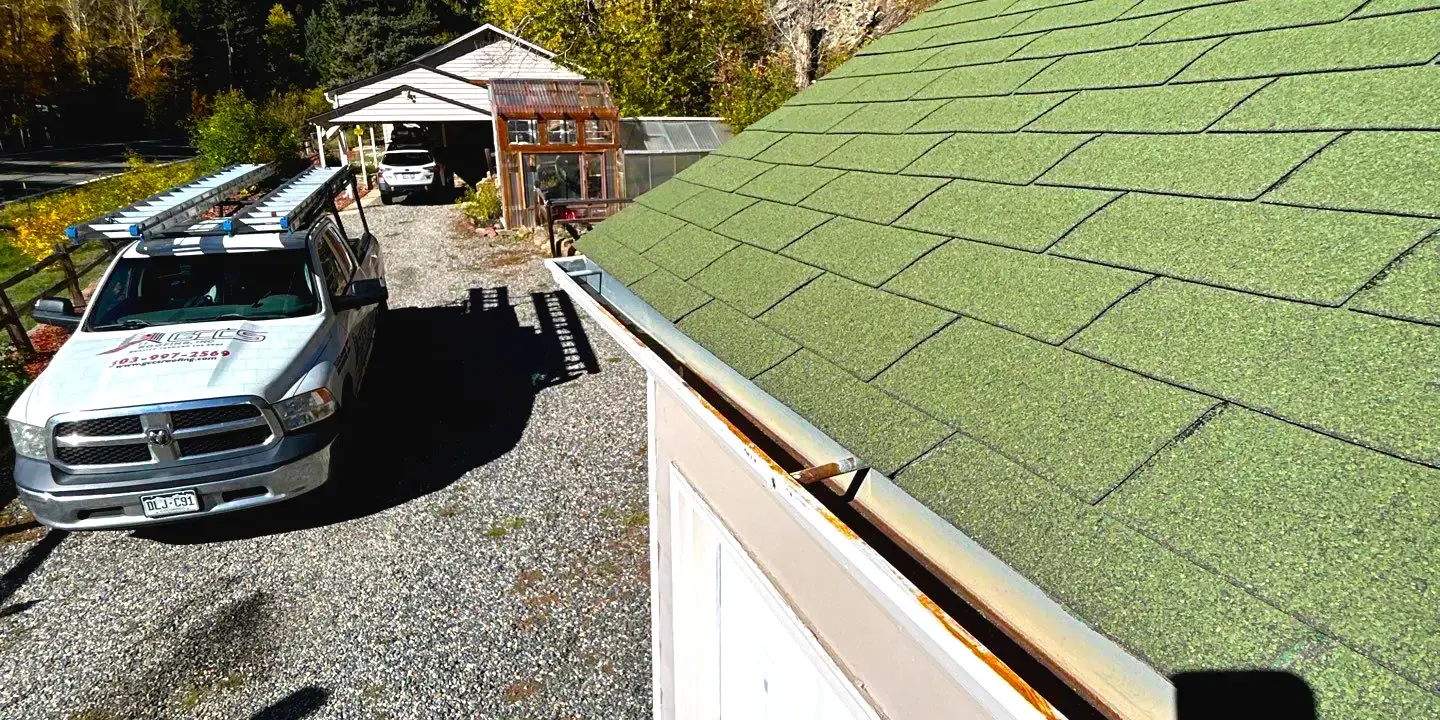 Rusting metal gutter Misaligned, rusting metal gutter along the edge of a green asphalt-shingle roof.