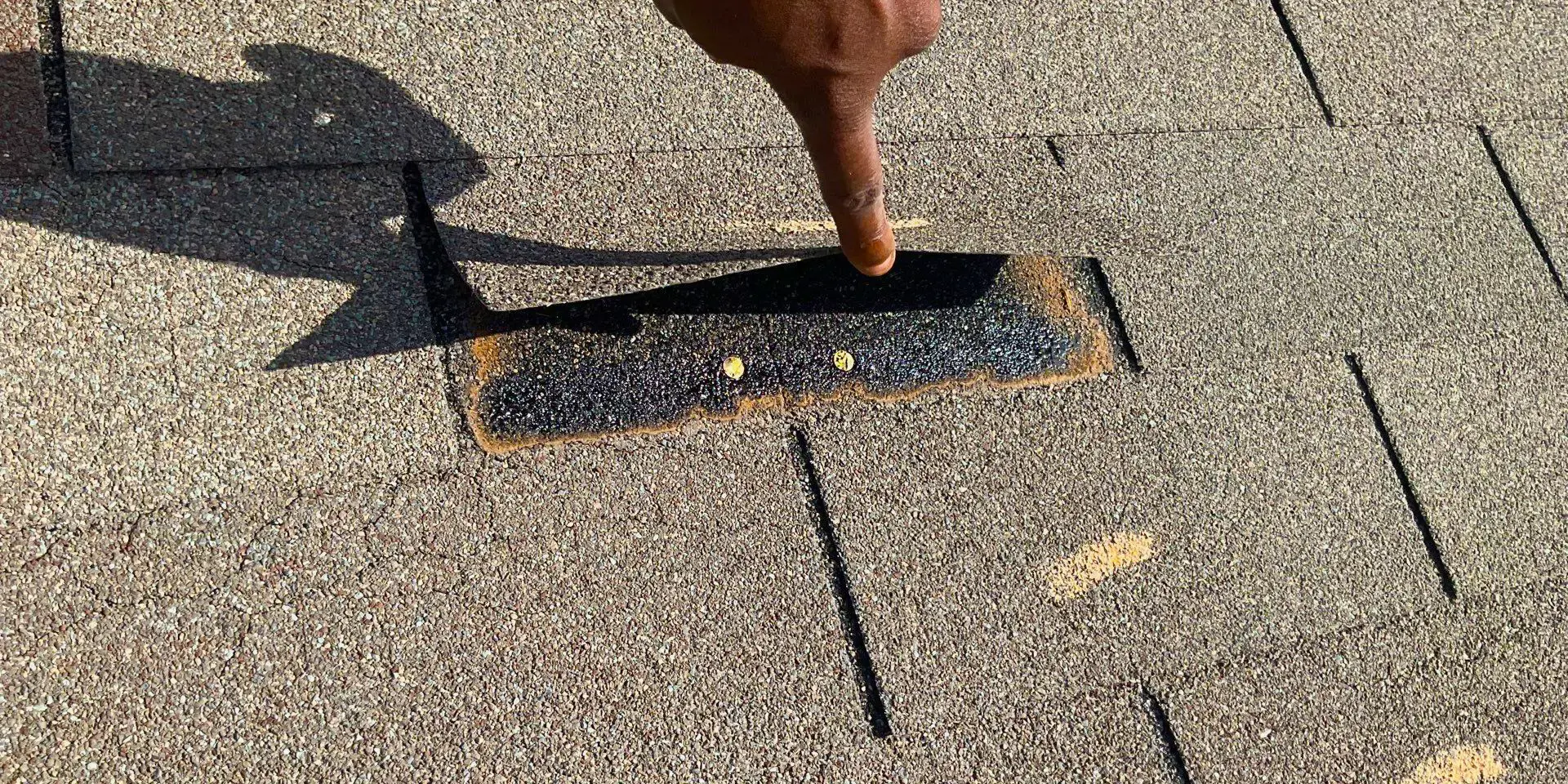 Shingle lifted to reveal an incorrectly placed nail, positioned too high above the nailing strip.