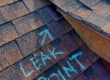 Asphalt shingle roof with “LEAK POINT” chalked pointing to faulty flashing at a roof-to-wall/valley intersection—illustrating a common Colorado roof leak that needs repair.