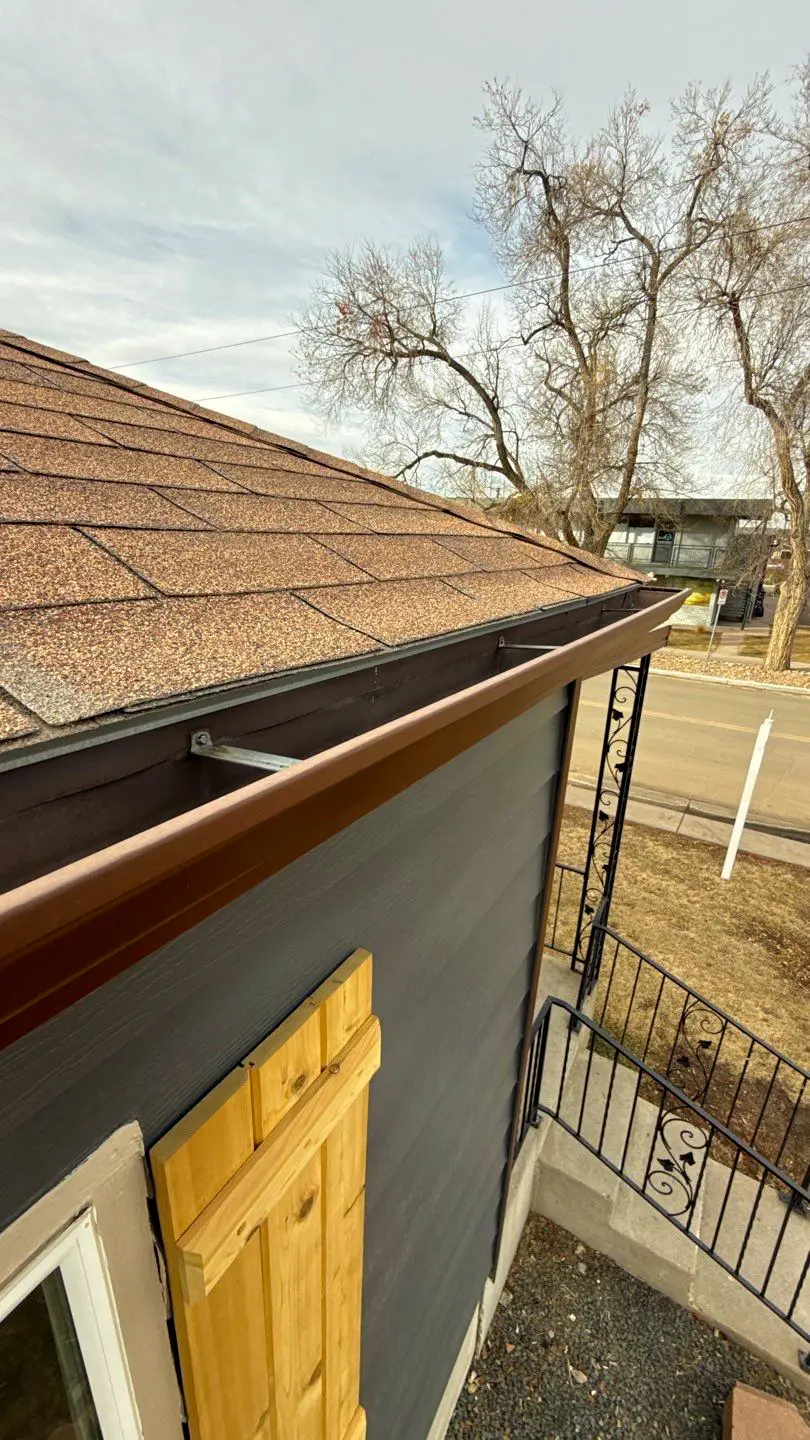 Newly installed gutter along asphalt shingle roof of a home in Littleton, CO.
