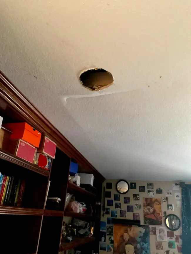 Hole and crack after roof damage Hole and crack in a bedroom ceiling from a water leak after roof damage, showing interior moisture intrusion and the need for urgent roof repair.