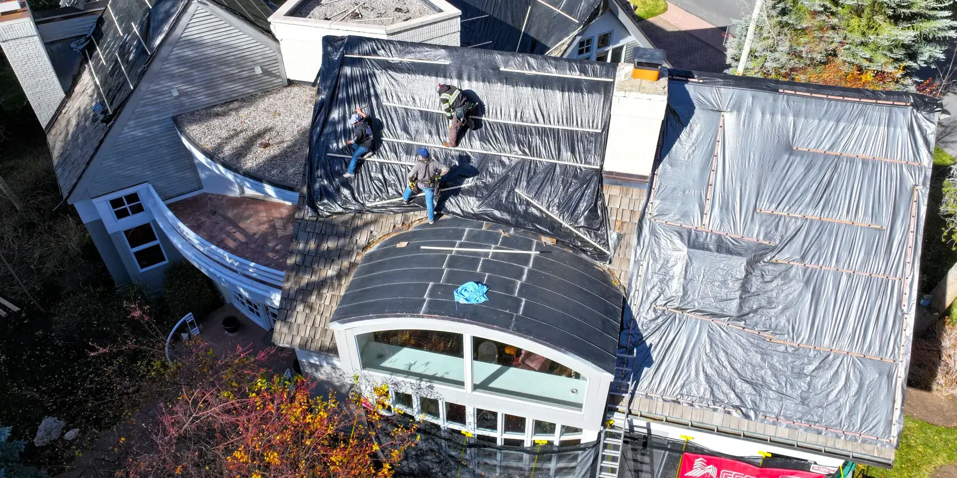 Roofers installing protective tarps Roofers installing protective tarps during a complex residential roof repair project