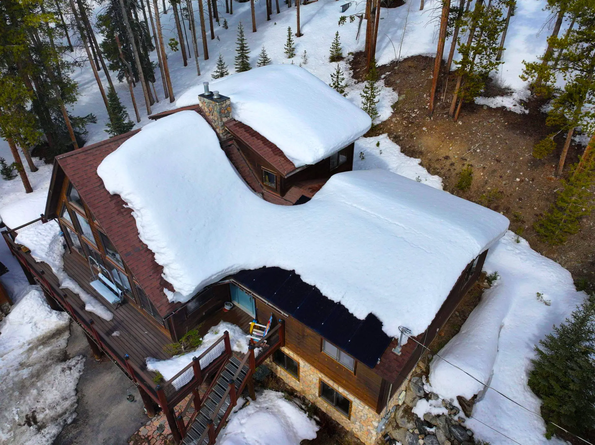 Snow-covered cabin roof in Littleton, CO showing heavy snow buildup and potential for winter roof leaks.