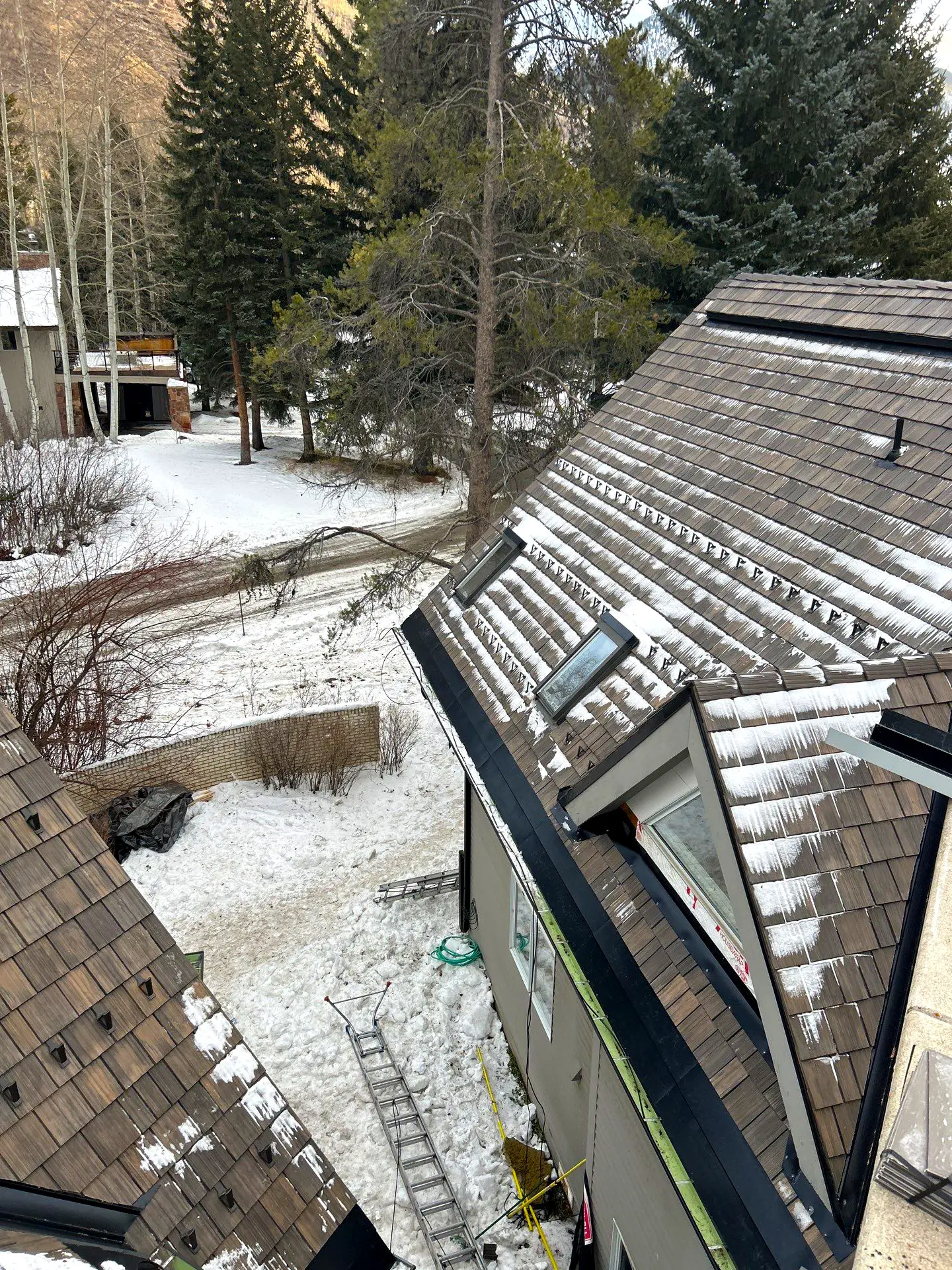 Sloped residential roof with shake-style shingles and partial snow accumulation