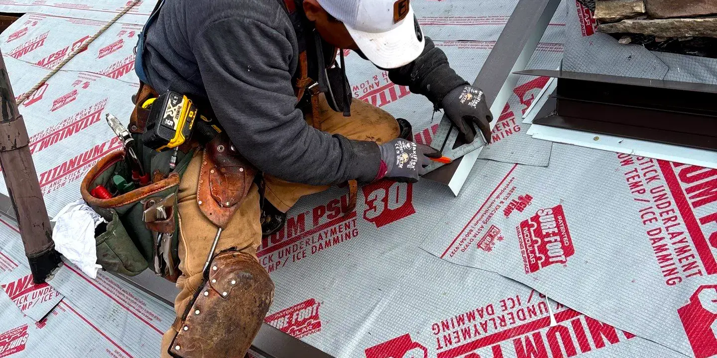 Professional roofer installing metal flashing at the base of a chimney, a critical detail to prevent leaks and ensure long-term roof durability in Littleton, Colorado.