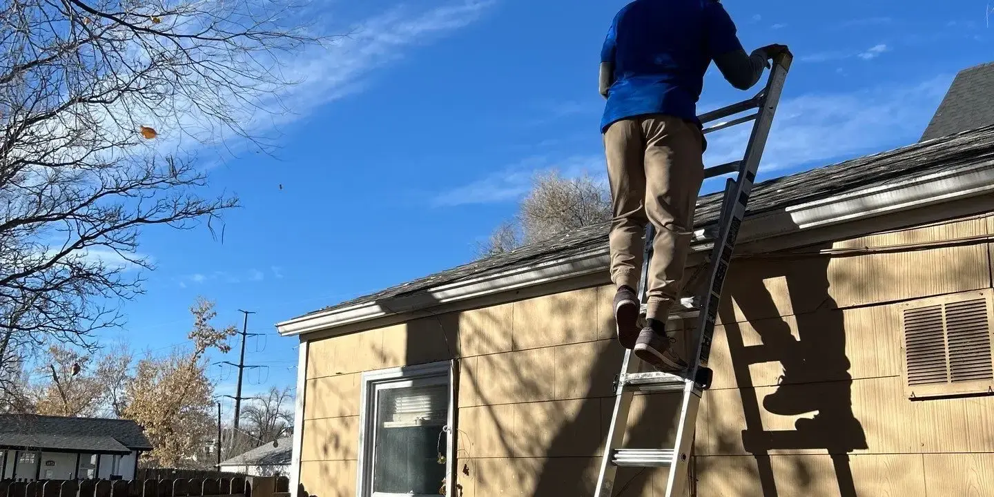 Roof inspection Roofing technician performing a roof inspection from a ladder on a residential home