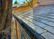 Gutter filled with dry autumn leaves along the roofline of a home, showing blockage and the need for cleaning to prevent drainage damage.