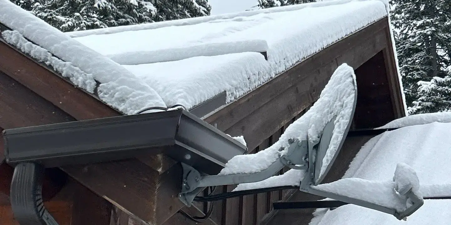 Snow-covered residential roof Snow-covered residential roof in a wooded area showing heavy snow accumulation.