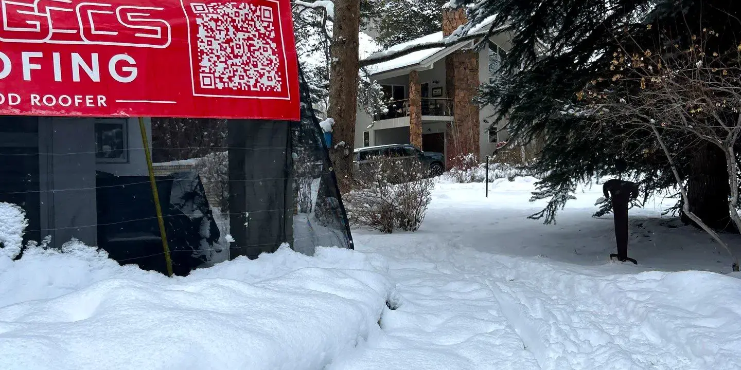Residential roof repair during heavy snowfall in Colorado GCCS Roofing completing a residential roof repair during heavy snowfall in Colorado, with the home and work area covered in snow, showcasing winter roofing maintenance and weather-resistant service.