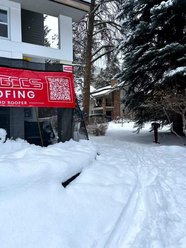 GCCS Roofing completing a residential roof repair during heavy snowfall in Colorado, with the home and work area covered in snow, showcasing winter roofing maintenance and weather-resistant service.