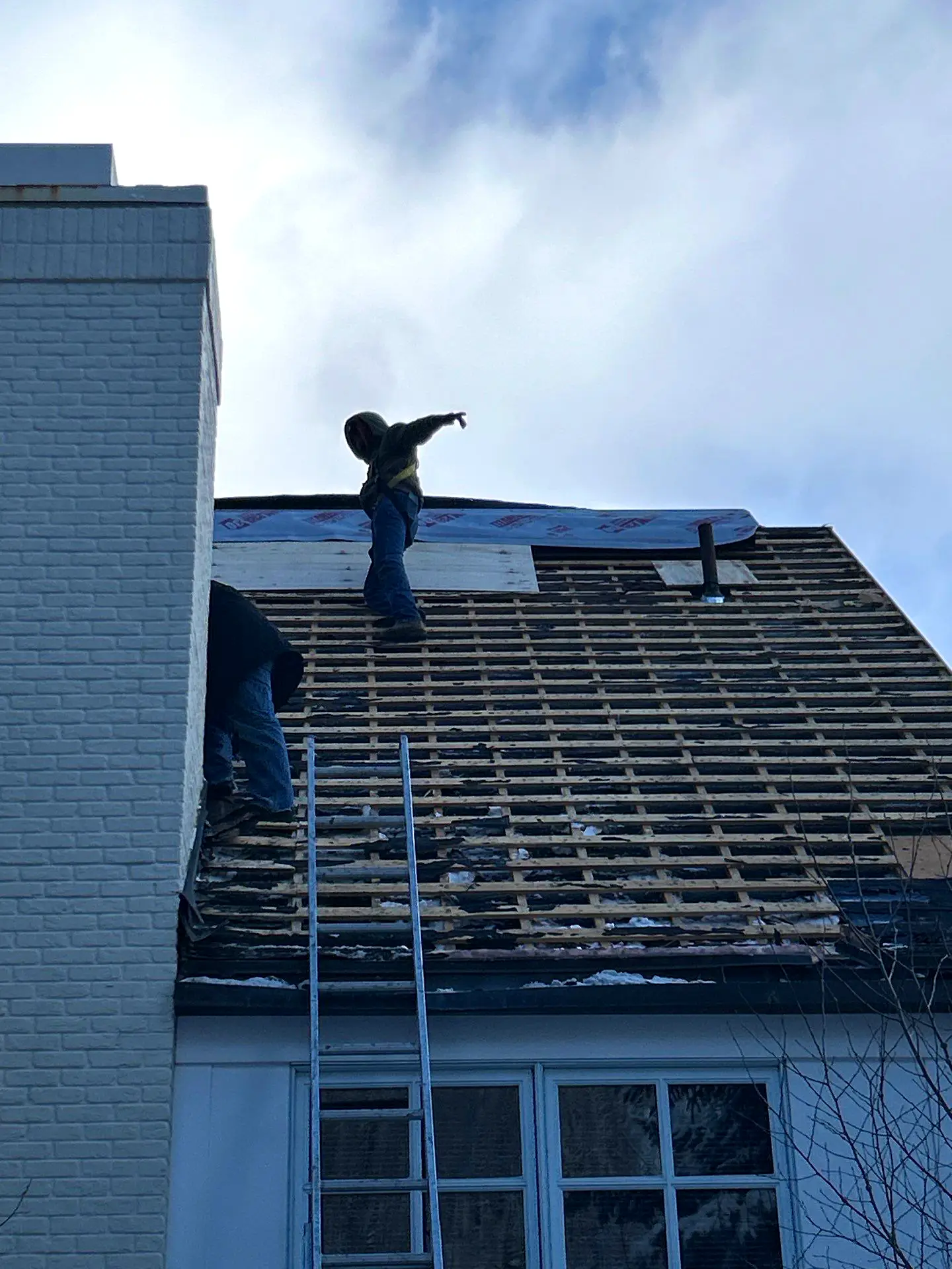 Experienced roofers removing old shingles and preparing the roof structure for a full roofing repair and replacement on a residential home.