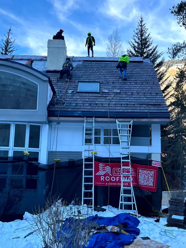 Roofing team working on a roof in winter to prevent damage caused by extreme temperature changes in Colorado.