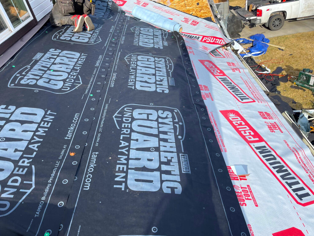 Installation of synthetic roofing underlayment on a residential roof, showing protective layers applied before shingles to improve waterproofing and durability.