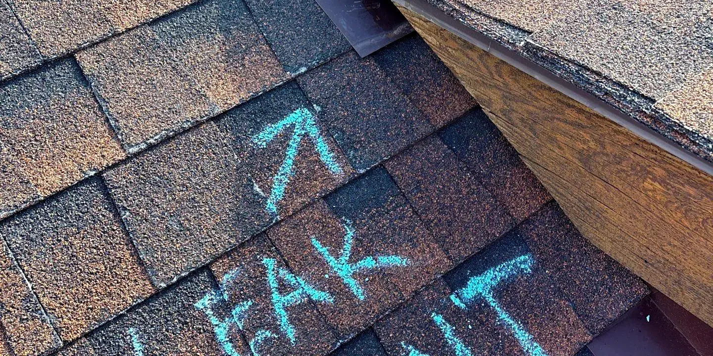 Marked leak Close-up of asphalt shingle roof showing damage and a marked leak point during a professional roof repair inspection in Littleton, CO.