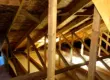 Interior view of a residential attic showing wooden roof trusses, roof decking, and insulation, illustrating structural framing and potential areas for hidden roof leaks or attic water damage.