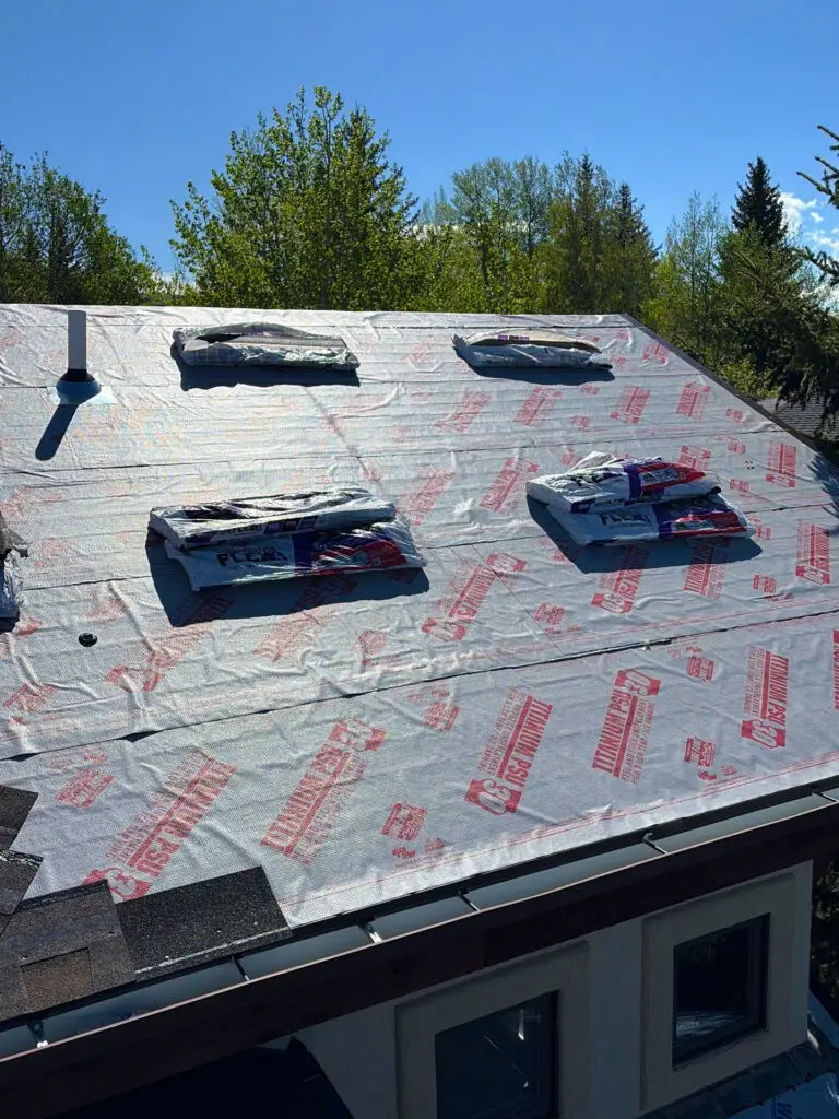 Synthetic underlayment installation on a residential roof during a roofing replacement project.