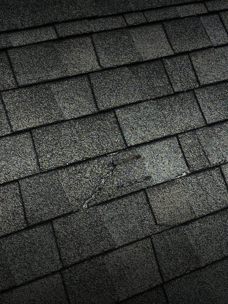 worn asphalt shingles with visible granule loss and surface damage, showing signs that the roof may need professional inspection or repair.