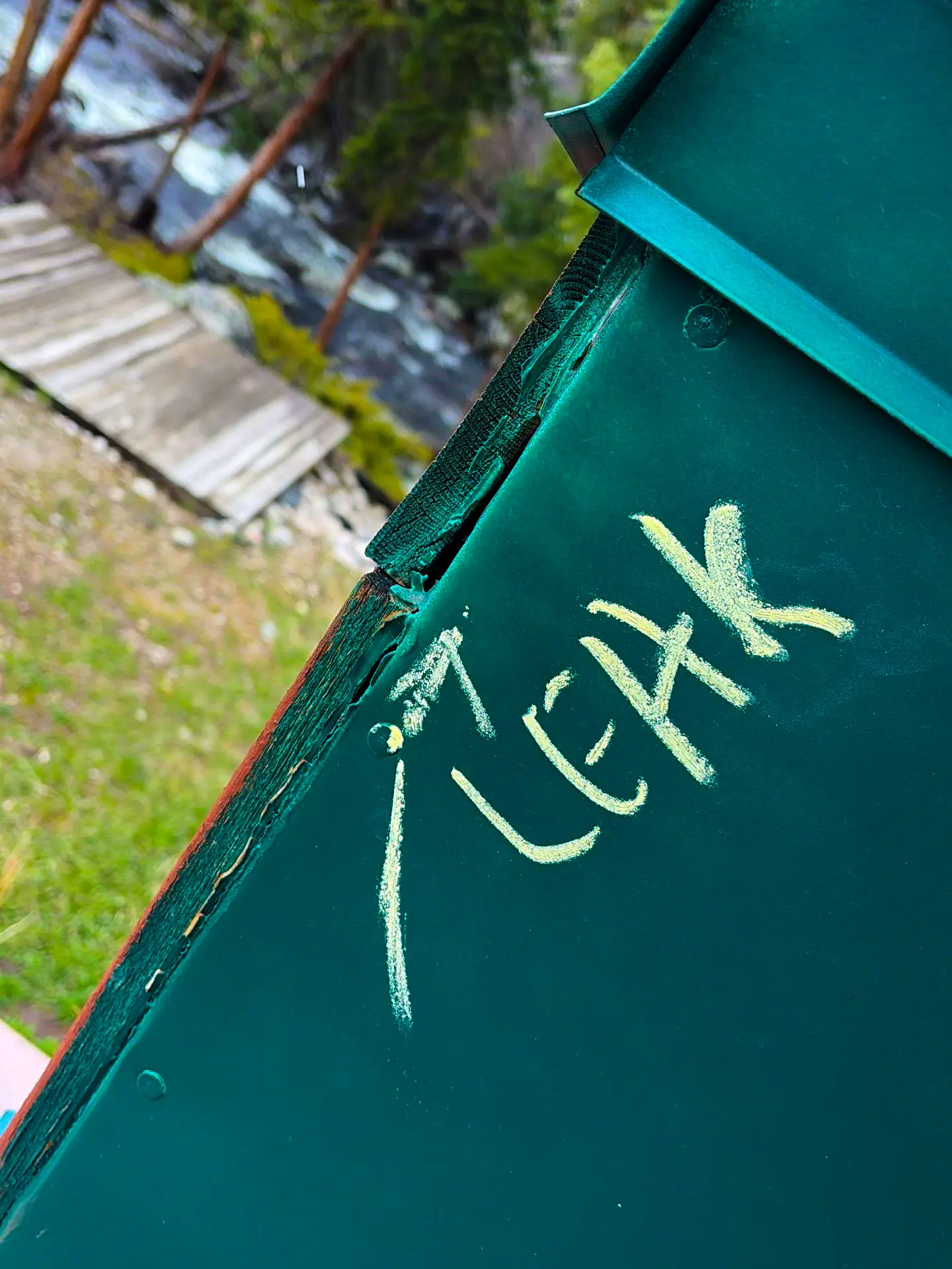 damaged green metal roof section with chalk marks indicating a visible leak point near the edge.