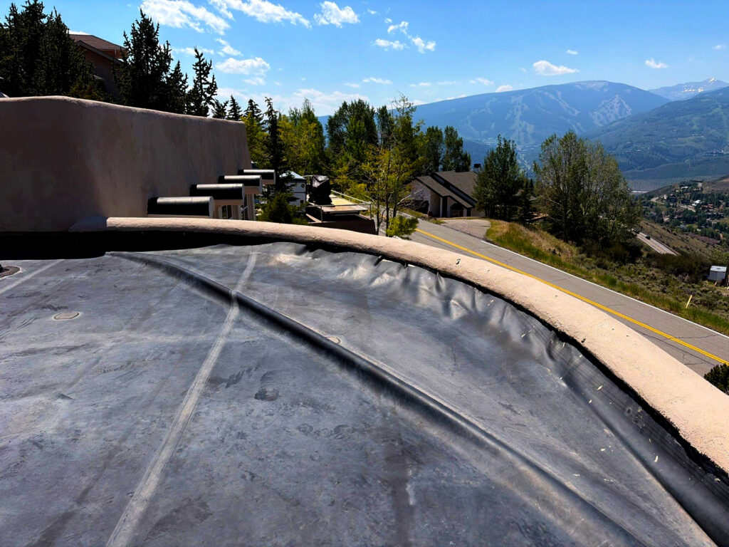 Flat roof membrane on a mountain property in Avon, Colorado, with visible parapet details and scenic valley views in the background.