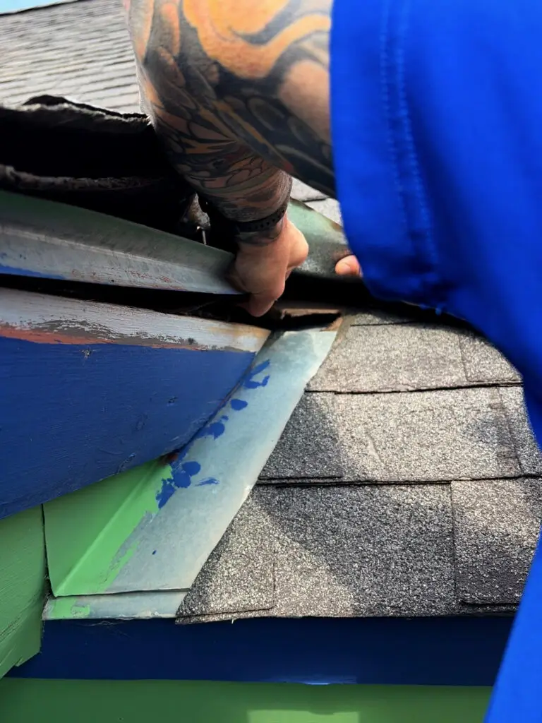 Roofer inspecting flashing and asphalt shingles during a professional roof inspection.