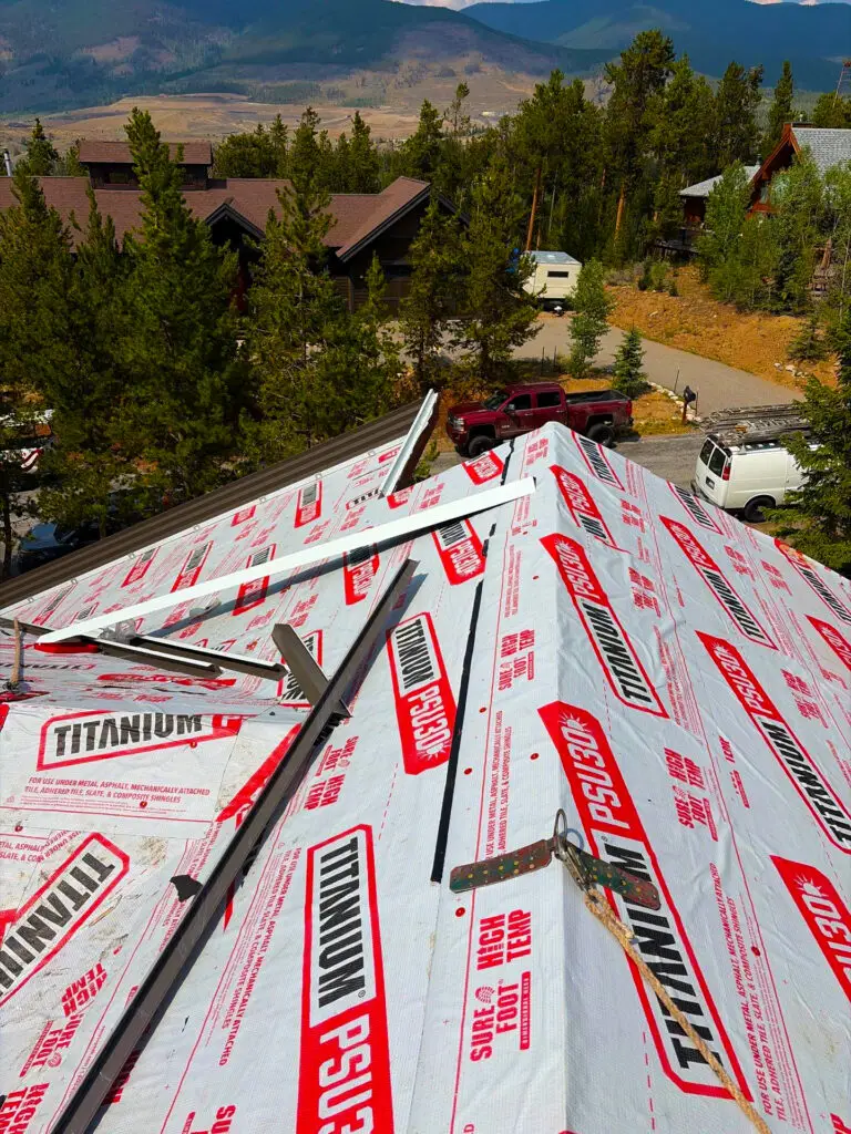Roofing installation in Avon, CO with synthetic underlayment and metal roofing panels on a mountain home.